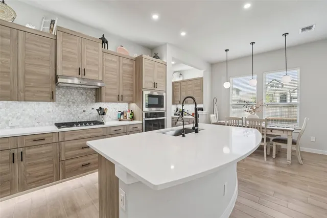 a kitchen with kitchen island a stove a sink a refrigerator and chairs