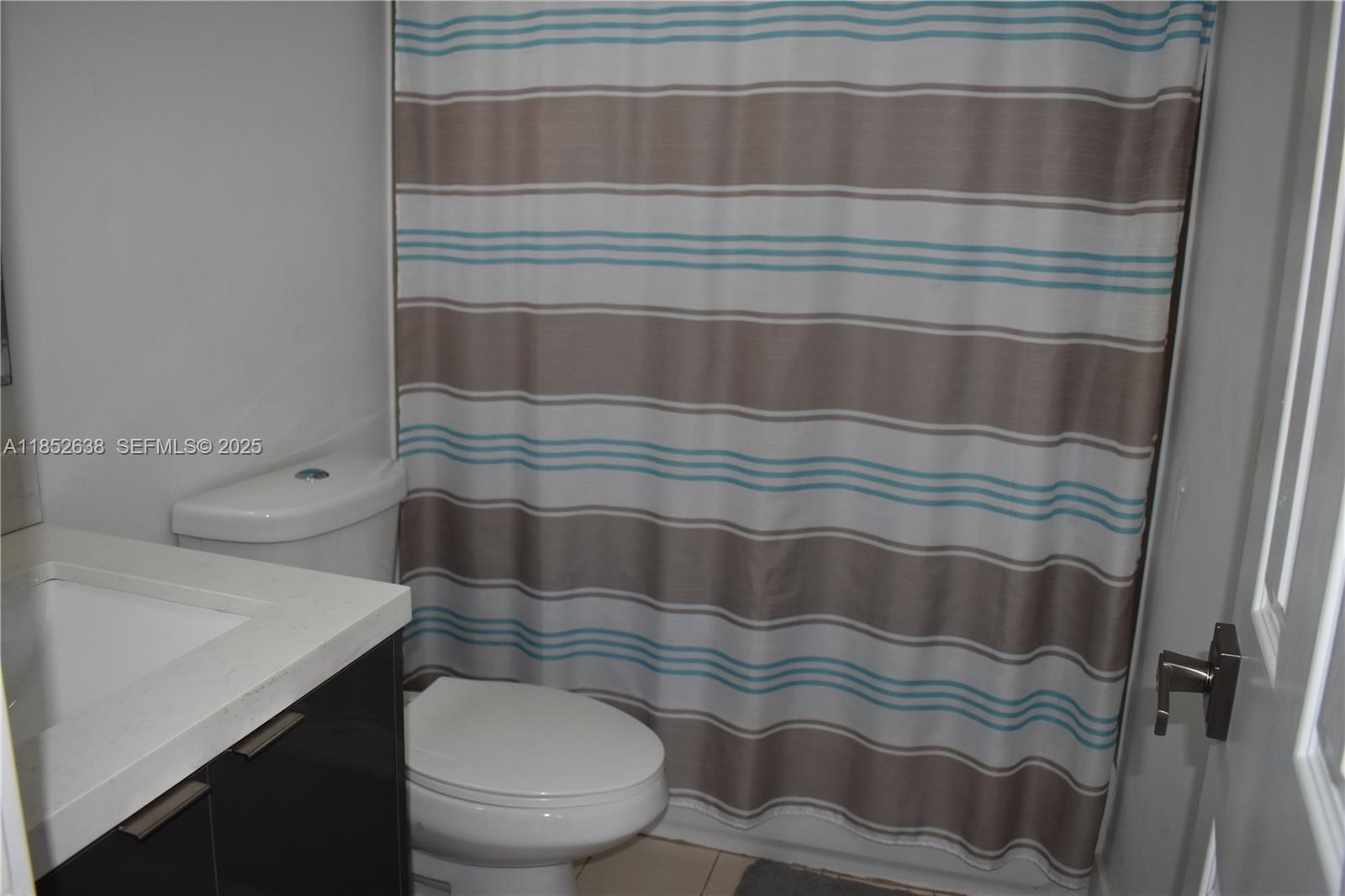5189 Northwest 108th Path Doral, FL 33178 - Photo 14 of 23 a bathroom with a toilet and a shower curtain