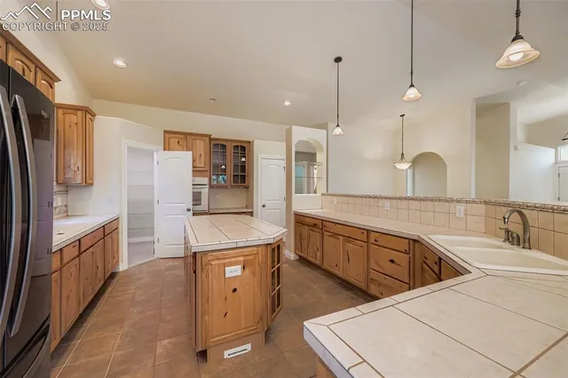 a large kitchen with kitchen island a large counter space a sink stainless steel appliances and cabinets