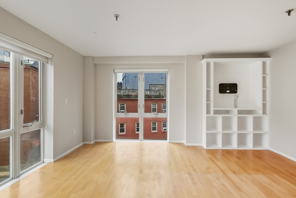 a view of an empty room with a window and wooden floor