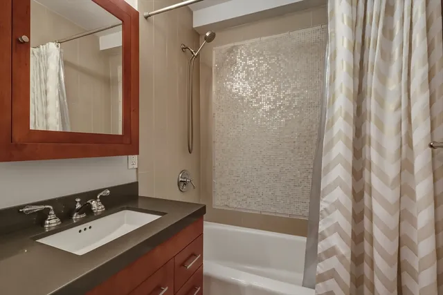 a bathroom with a bathtub sink vanity and mirror