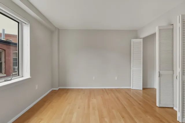 a view of an empty room with wooden floor and a window