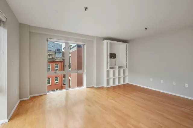 a view of a livingroom with wooden floor and a bathroom
