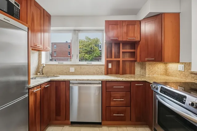 a kitchen with stainless steel appliances granite countertop a sink and wooden cabinets