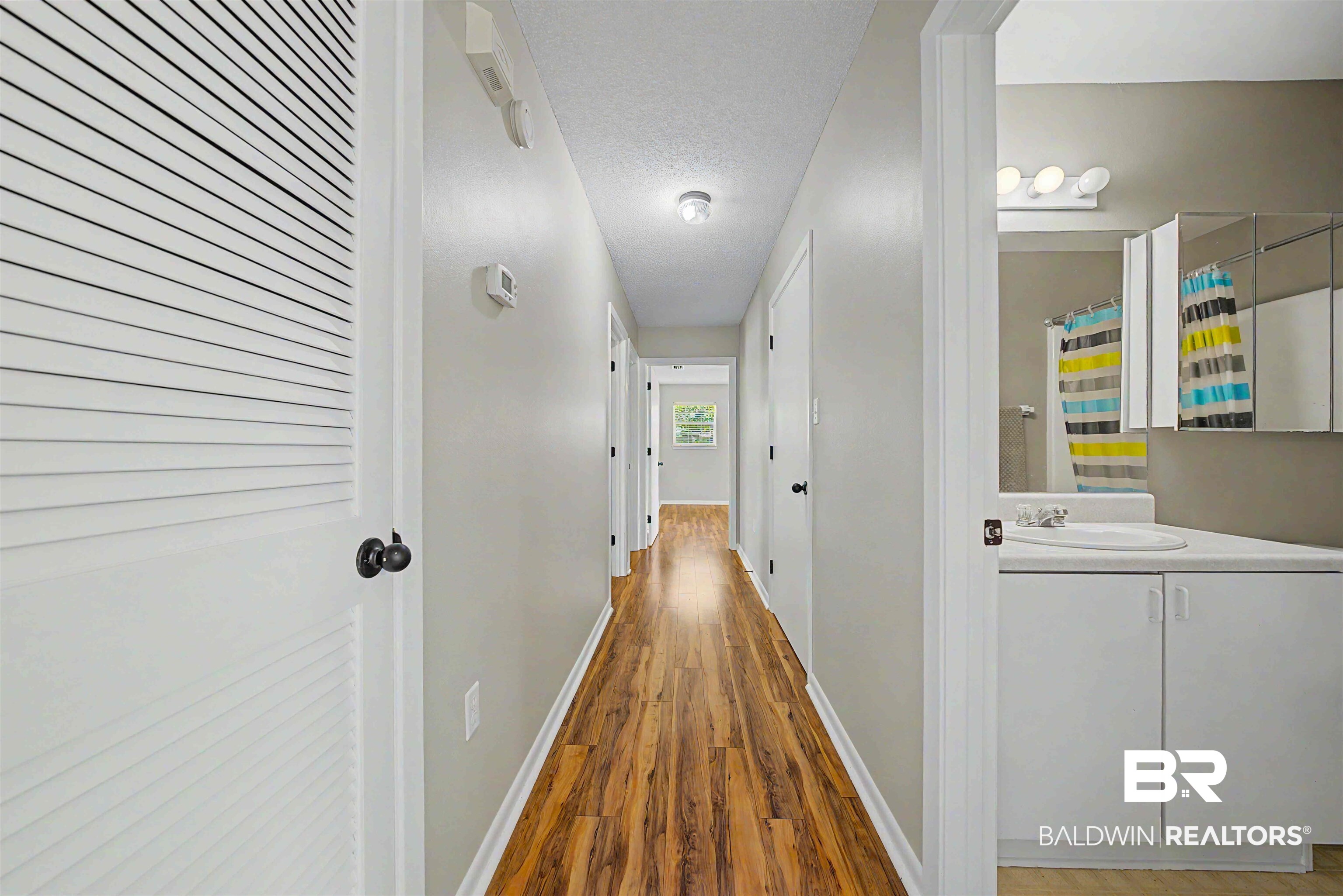 22963 Highway 98 Foley, AL 36535 - Photo 16 of 52 Hallway featuring wood-finish flooring, light gray wall paint, white trim, and a ceiling-mounted light fixture