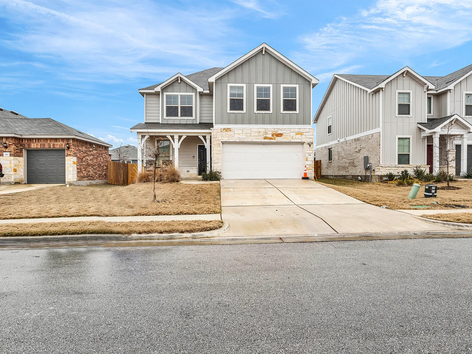 156 Janice Road Taylor, TX 76574 - Photo 1 of 29 View of front facade with board and batten siding, a porch, stone siding, an attached garage, and concrete driveway