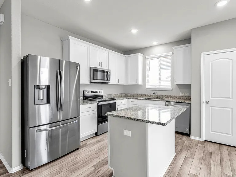 156 Janice Road Taylor, TX 76574 - Photo 9 of 29 Kitchen featuring light stone countertops, light wood-style flooring, white cabinetry, a sink, and stainless steel appliances