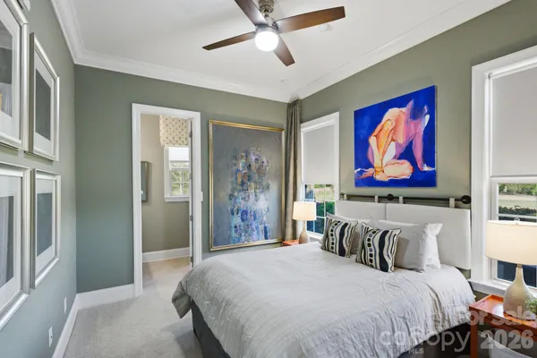 a bedroom with bed and paintings on the wall
