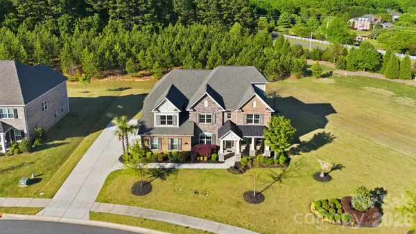an aerial view of a house with swimming pool and large trees