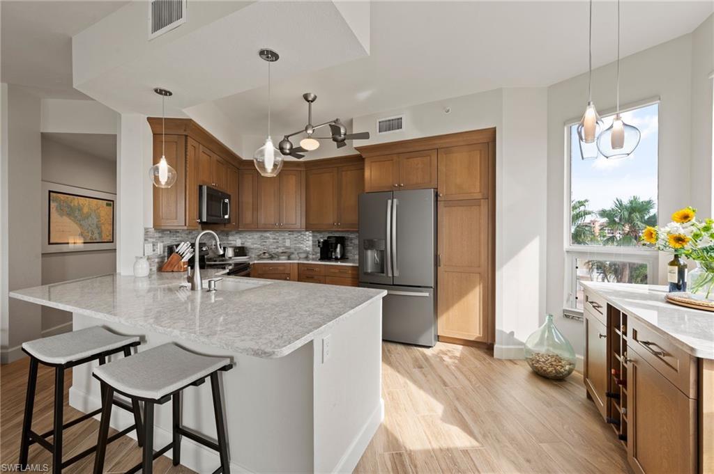 a kitchen with stainless steel appliances granite countertop a sink a stove a refrigerator cabinets and dining table