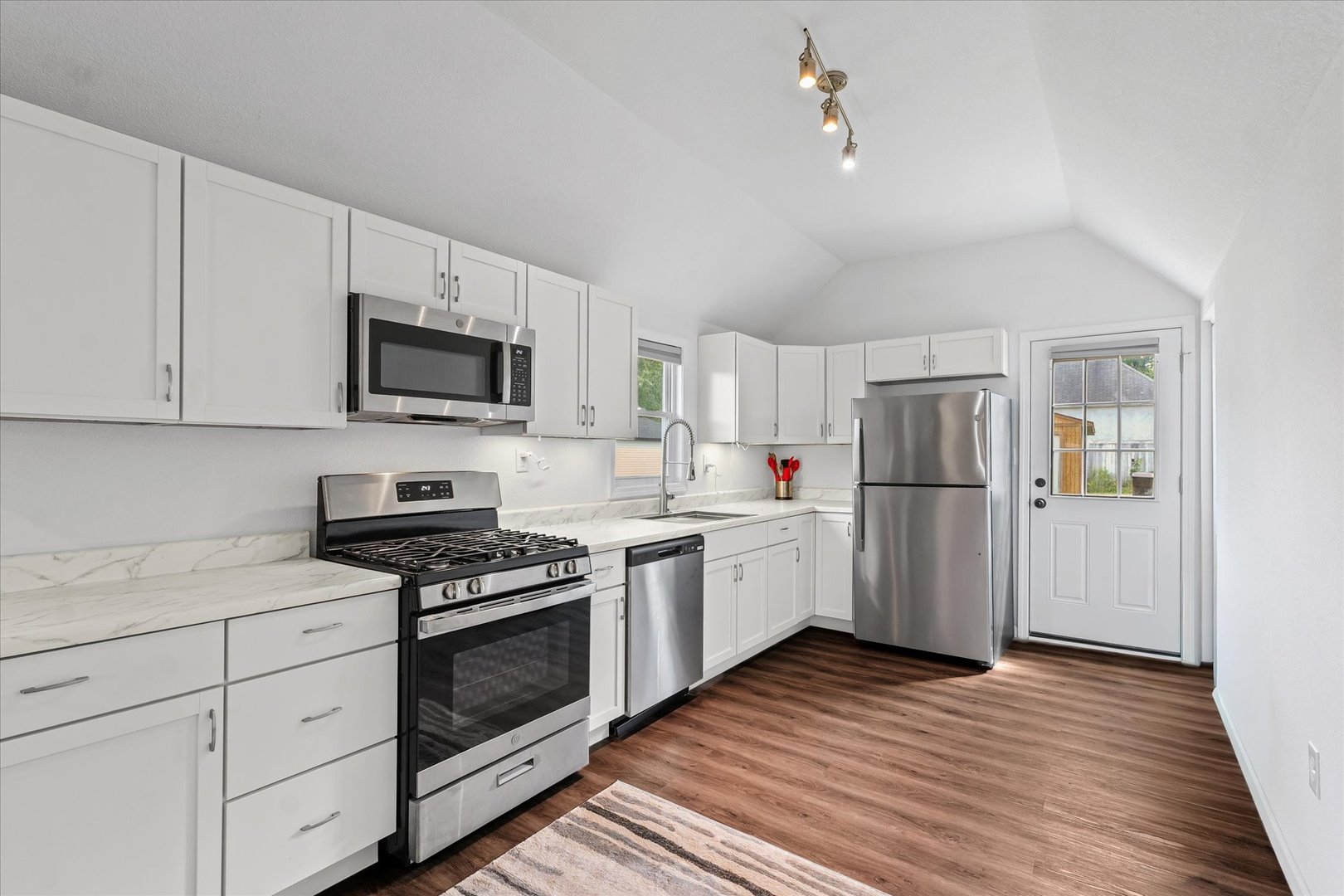 107 Front Street Fisher, IL 61843 - Photo 9 of 25 a kitchen with a refrigerator a stove top oven a sink and dishwasher with wooden floor