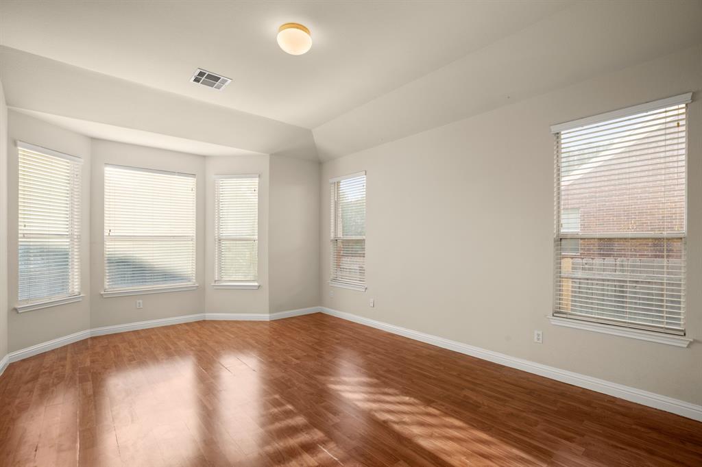 10105 Wind Cave Trail Austin, TX 78747 - Photo 10 of 23 Room featuring wood-finish flooring, a bay window with three panels, additional window fenestration, a tray ceiling, and a flush mount ceiling light