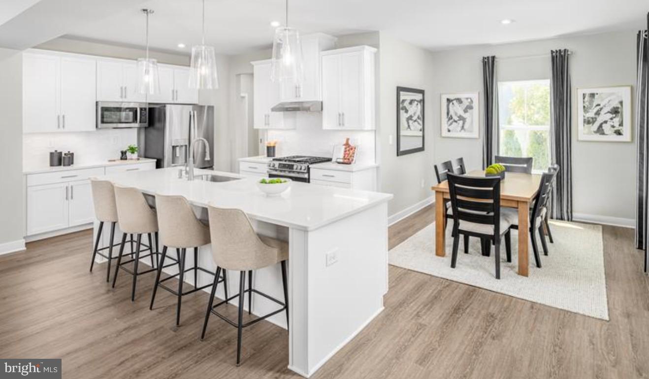 1410 Leeland Forest Road, Unit 25 Upper Marlboro, MD 20774 - Photo 4 of 21 a kitchen with stainless steel appliances kitchen island granite countertop a table chairs and a refrigerator
