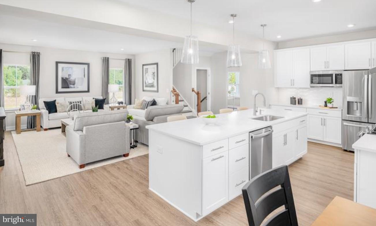 1410 Leeland Forest Road, Unit 25 Upper Marlboro, MD 20774 - Photo 5 of 21 a large white kitchen with stainless steel appliances kitchen island granite countertop a lot of white cabinets and wooden floors