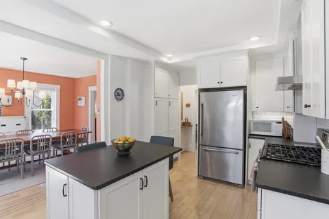 a kitchen with stainless steel appliances granite countertop a refrigerator a stove a sink a dining table and chairs