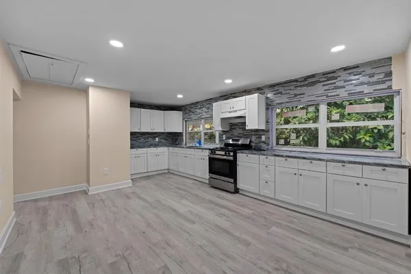 a kitchen with granite countertop white cabinets and stainless steel appliances
