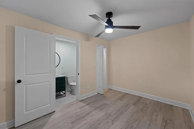 a view of empty room with wooden floor and ceiling fan