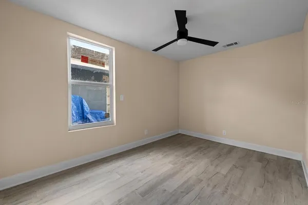 a view of an empty room with a window and wooden floor