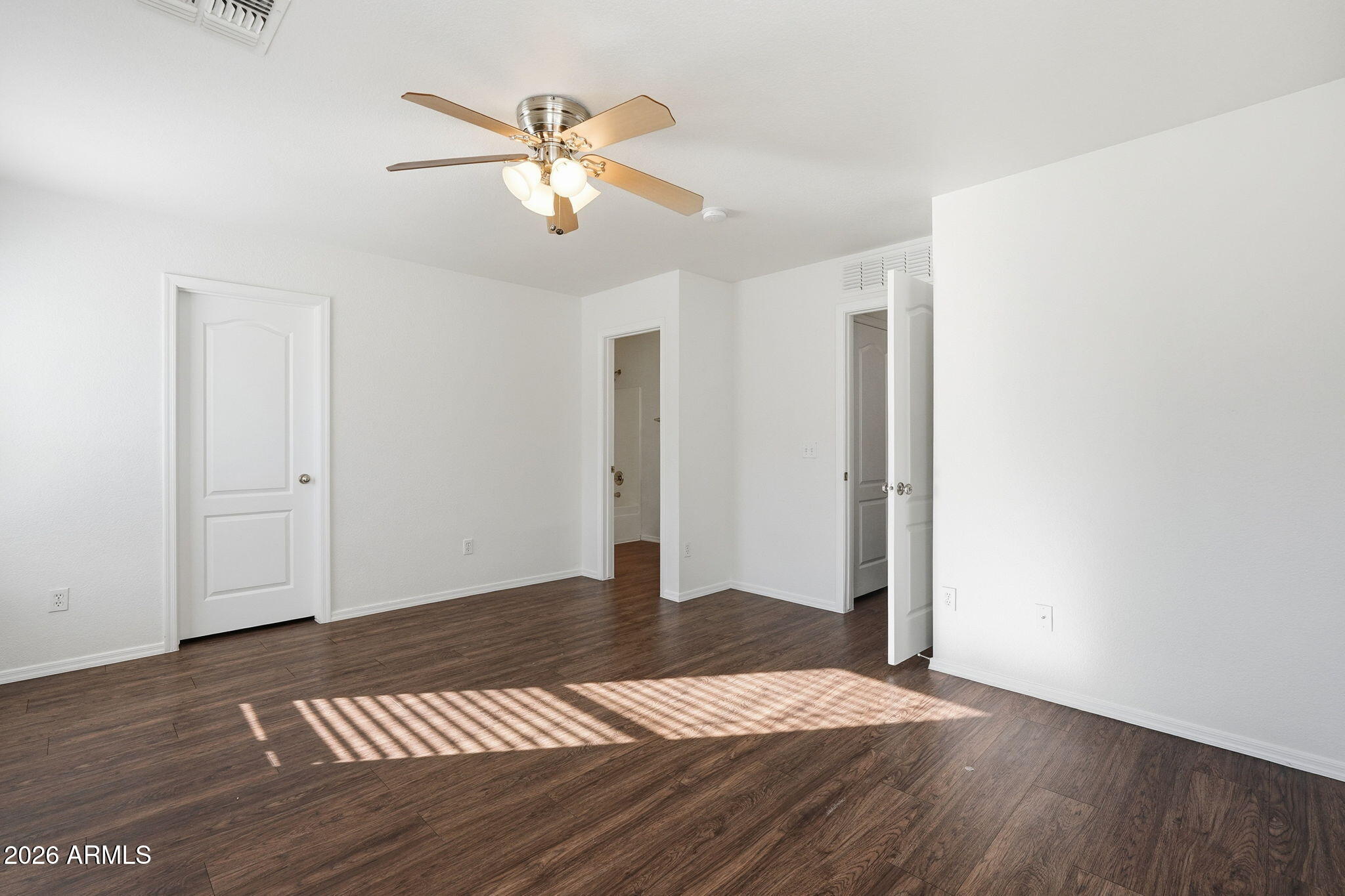 211 East Valley View Drive Phoenix, AZ 85042 - Photo 24 of 47 a view of an empty room with wooden floor and a ceiling fan