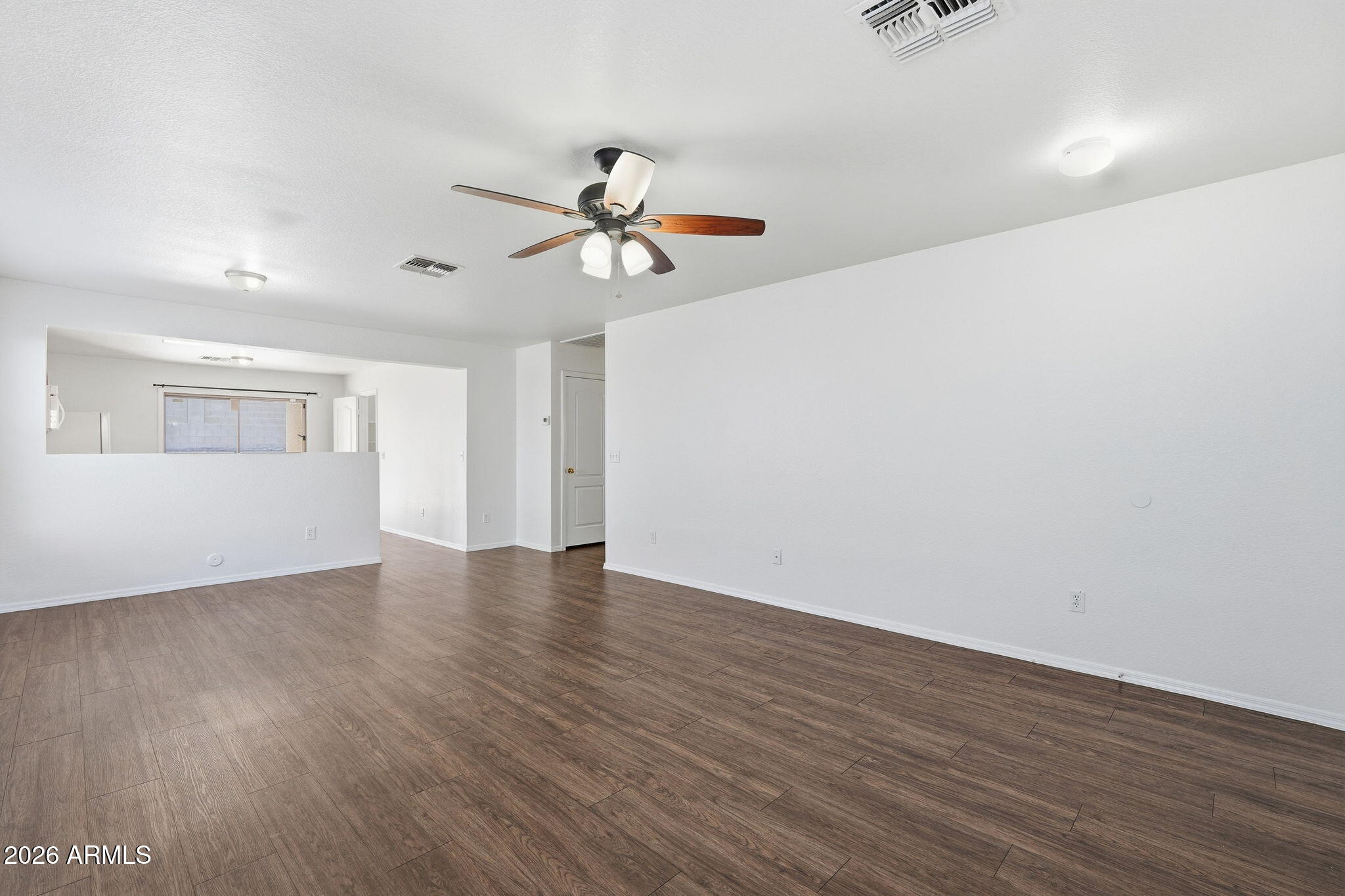 211 East Valley View Drive Phoenix, AZ 85042 - Photo 10 of 47 an empty room with wooden floor chandelier fan and windows