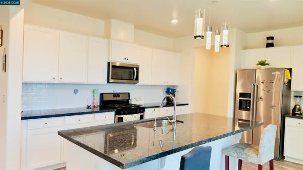 a kitchen with stainless steel appliances granite countertop a stove a sink and a refrigerator