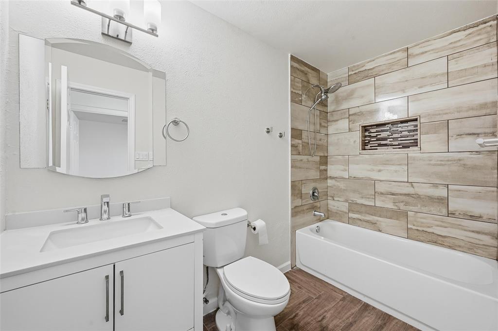 4645 Carr Street The Colony, TX 75056 - Photo 4 of 18 a bathroom with a toilet a sink a mirror a bathtub and vanity