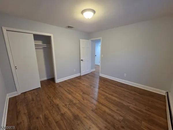 a view of an empty room with wooden floor and closet