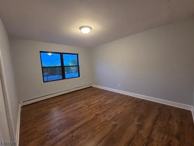 a view of an empty room with window and wooden floor