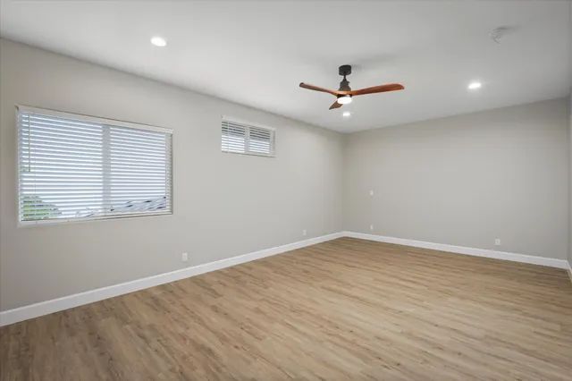 a view of an empty room with wooden floor and a mirror
