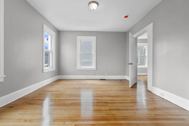 a view of an empty room with window and wooden floor