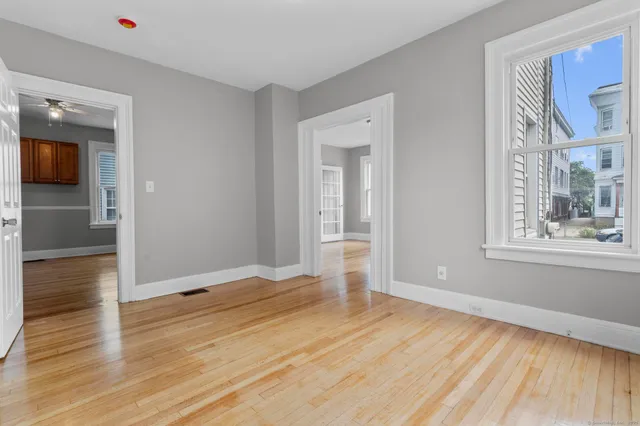 a view of empty room with wooden floor and fan