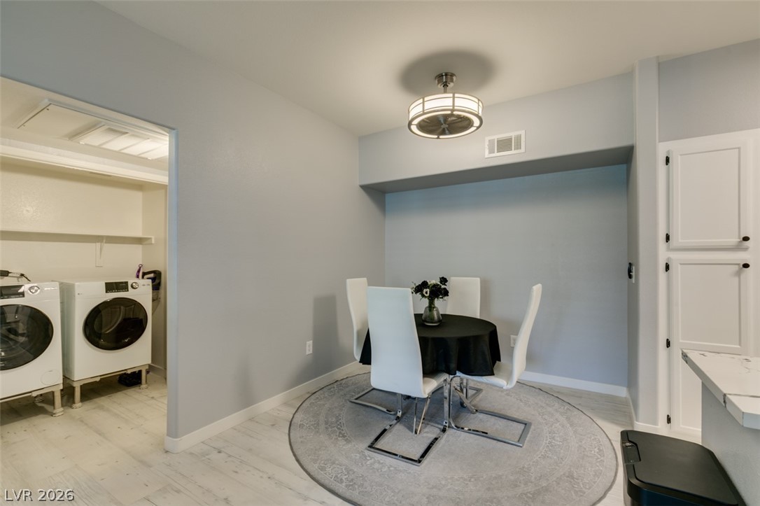 7255 West Sunset Road, Unit 1103 Las Vegas, NV 89113 - Photo 20 of 35 A compact dining space seamlessly integrates with a convenient laundry area, featuring light wood flooring and overhead lighting.