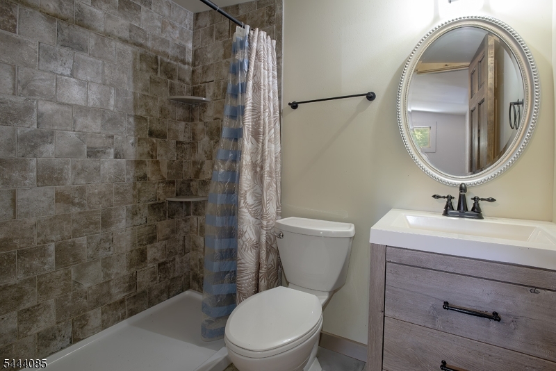 79 Lake Wallkill Road Vernon, NJ 07461 - Photo 9 of 27 a bathroom with a toilet sink vanity and mirror