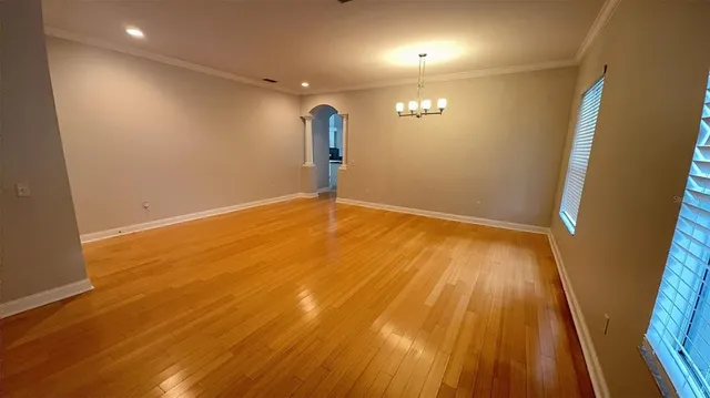 an empty room with wooden floor and a ceiling fan