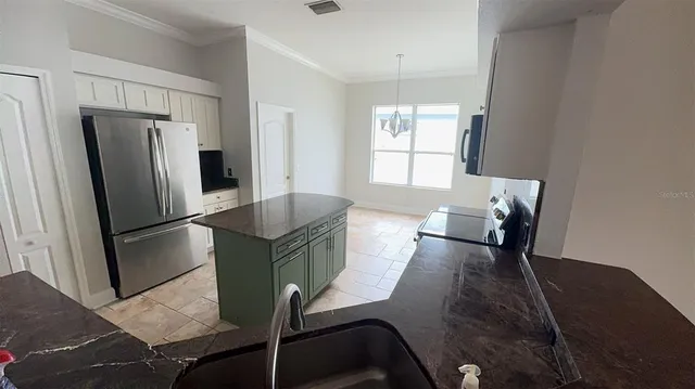 a kitchen with stainless steel appliances granite countertop a refrigerator a sink a stove and white cabinets