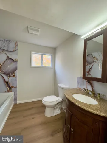 a bathroom with a granite countertop sink toilet and mirror