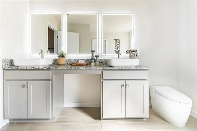 a bathroom with a granite countertop sink and a toilet