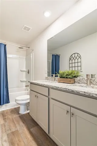 a bathroom with a granite countertop sink mirror bathtub and toilet