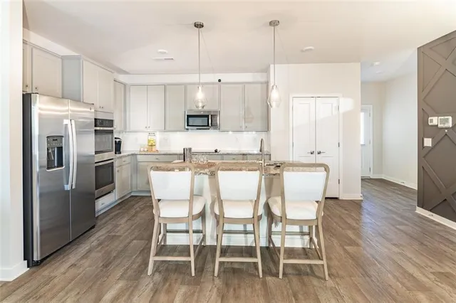 a kitchen with stainless steel appliances a dining table chairs refrigerator and sink
