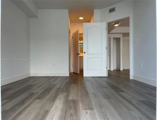 a view of a hallway with wooden floor and a refrigerator