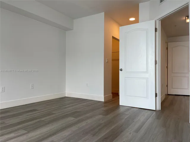 a view of an empty room with wooden floor and closet