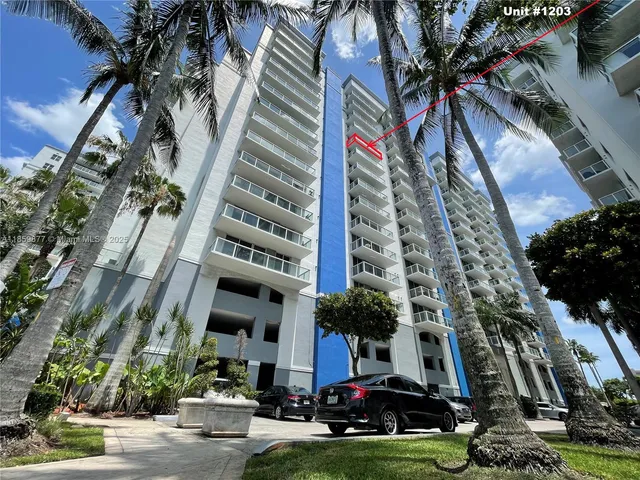a front view of a multi story residential apartment building with yard and parking space