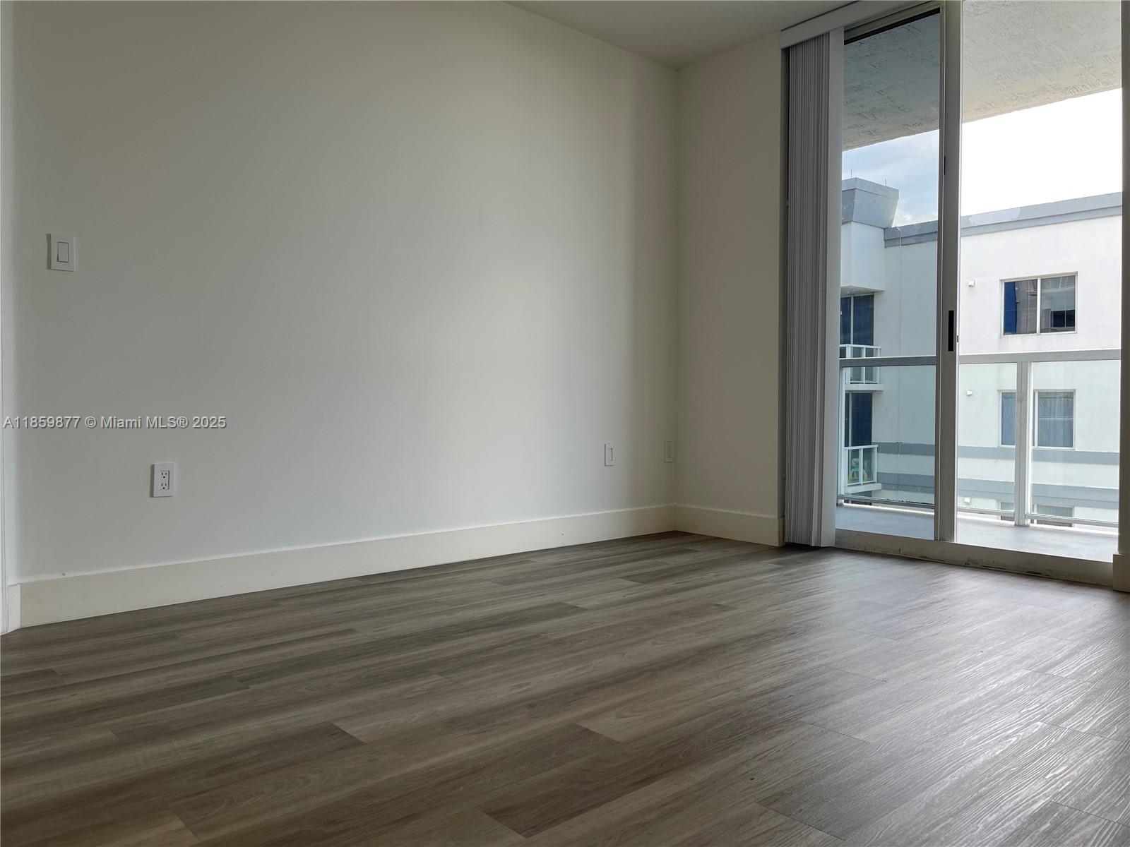 5085 Northwest 7th Street, Unit 1203 Miami, FL 33126 - Photo 22 of 26 a view of an empty room with wooden floor and a window
