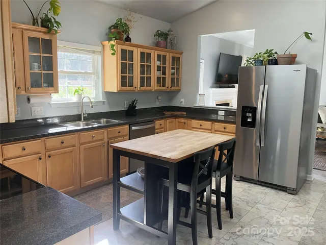 a kitchen with stainless steel appliances granite countertop a dining table chairs stove refrigerator and microwave