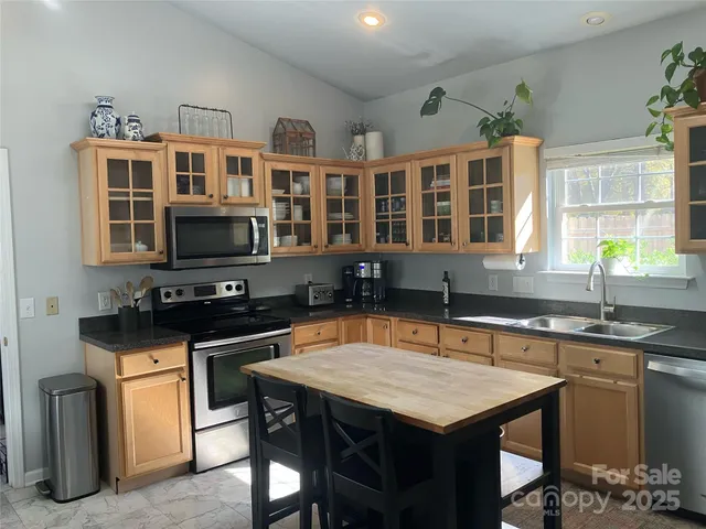 a kitchen with stainless steel appliances granite countertop a stove a sink a microwave and a refrigerator