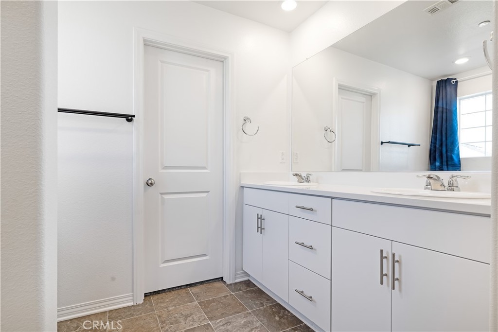 2498 Gunner Ridge Way Rialto, CA 92377 - Photo 13 of 31 a bathroom with a double vanity sink and mirror