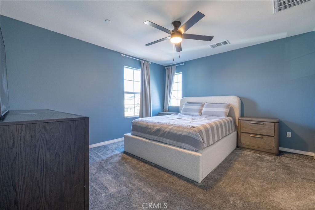 2498 Gunner Ridge Way Rialto, CA 92377 - Photo 16 of 31 a bedroom with a large bed and a chandelier