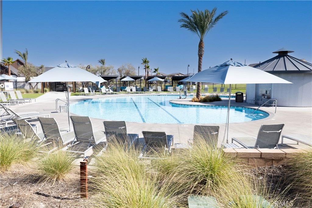 2498 Gunner Ridge Way Rialto, CA 92377 - Photo 30 of 31 a view of a swimming pool with a table and chairs under an umbrella