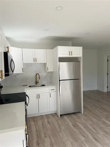 a kitchen with granite countertop a refrigerator sink and cabinets