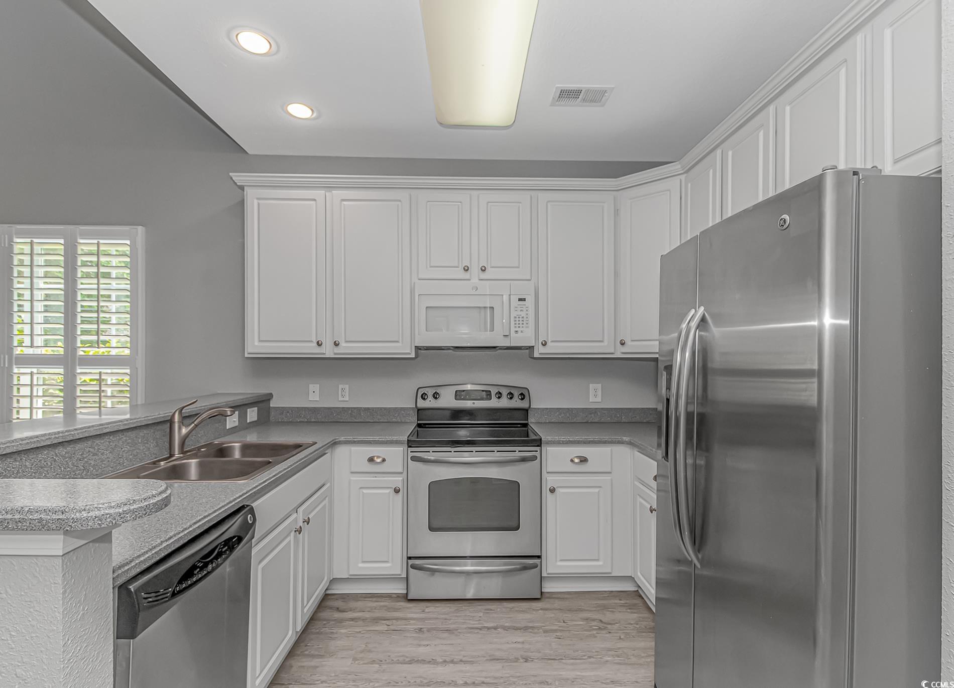 751 Painted Bunting Drive, Unit E Murrells Inlet, SC 29576 - Photo 11 of 40 Kitchen with stainless steel appliances, a sink, a peninsula, recessed lighting, and white cabinetry